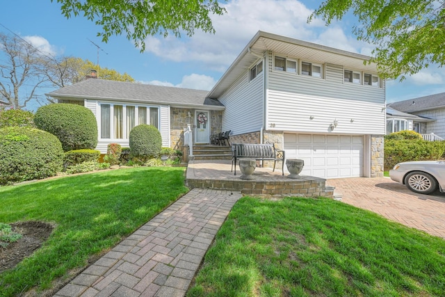 tri-level home featuring a garage, a chimney, a front lawn, and stone siding