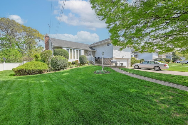split level home with a front lawn, fence, and a chimney