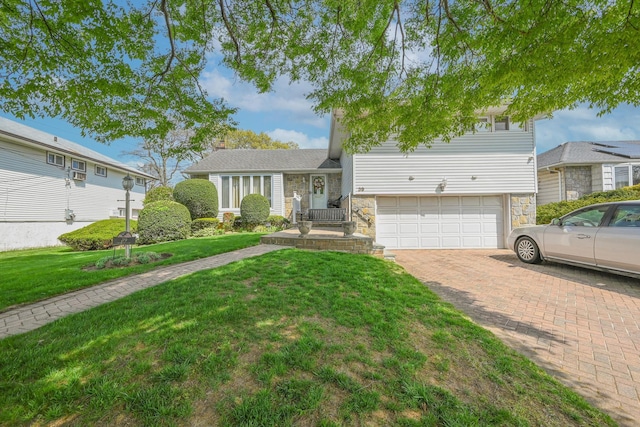 tri-level home featuring decorative driveway, an attached garage, stone siding, and a front lawn