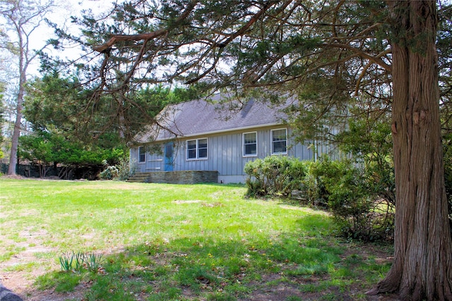 exterior space featuring board and batten siding, a shingled roof, and a yard
