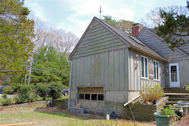 view of side of property with roof with shingles, a chimney, board and batten siding, and a garage