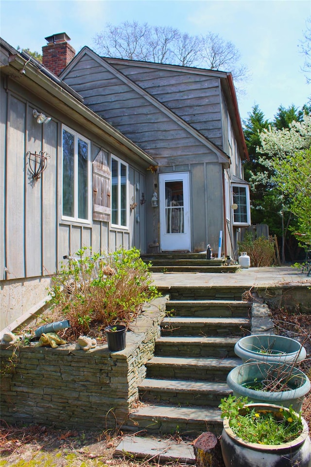 entrance to property featuring a chimney and board and batten siding