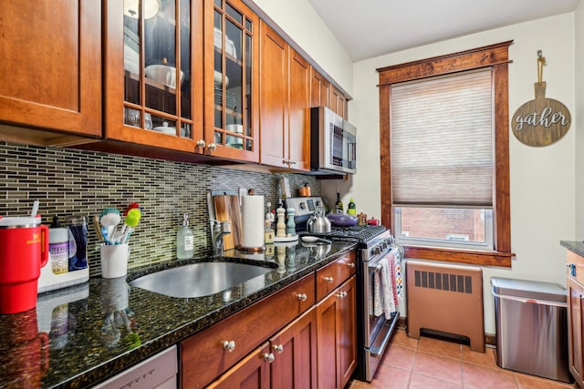 200 N Village Ave Unit D10, Rockville Centre, NY 11570 - kitchen featuring decorative backsplash, radiator heating unit, a sink, dark stone countertops, and stainless steel appliances