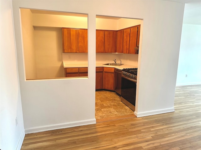 kitchen featuring a sink, brown cabinets, light wood-style flooring, and appliances with stainless steel finishes