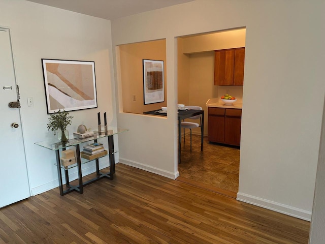 hallway featuring dark wood-type flooring and baseboards