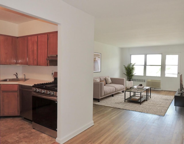 kitchen featuring a sink, stainless steel appliances, open floor plan, under cabinet range hood, and light countertops