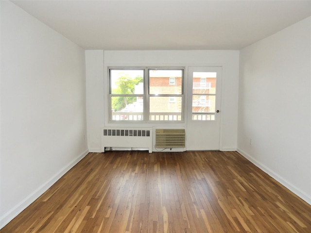 empty room with radiator, baseboards, and hardwood / wood-style flooring