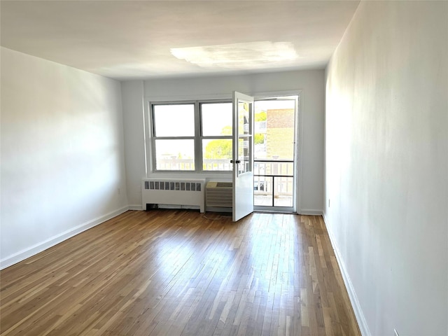 unfurnished room with baseboards, radiator, french doors, and hardwood / wood-style flooring