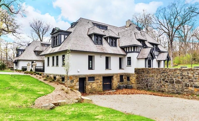 exterior space with stucco siding, a chimney, a front lawn, and stone siding