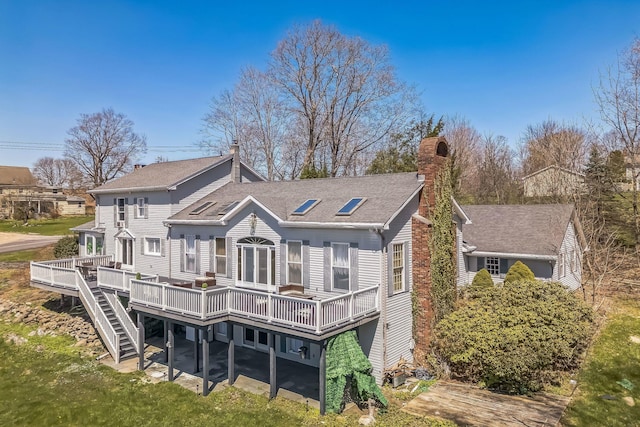 rear view of property with a chimney, a shingled roof, stairs, and a deck