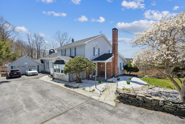 view of front of property featuring brick siding, a chimney, and a detached garage