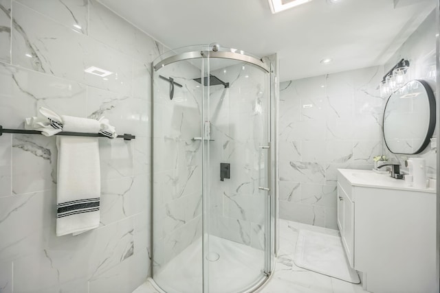 bathroom featuring vanity, marble finish floor, tile walls, recessed lighting, and a marble finish shower