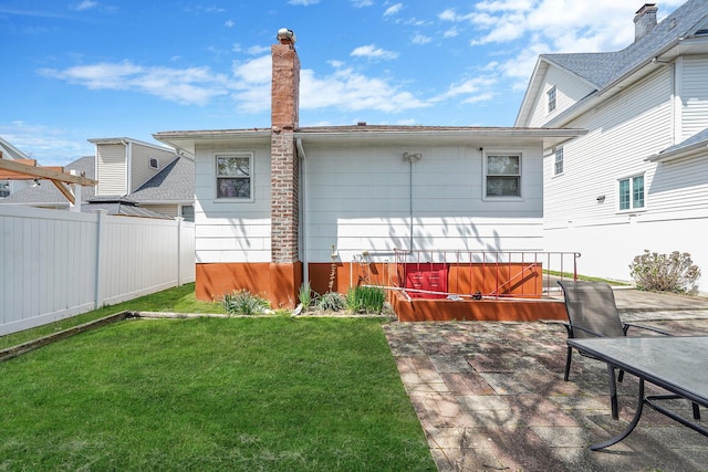 1036 Pacific St, Baldwin Harbor, NY 11510 - rear view of house with a lawn, fence, a chimney, and a patio area