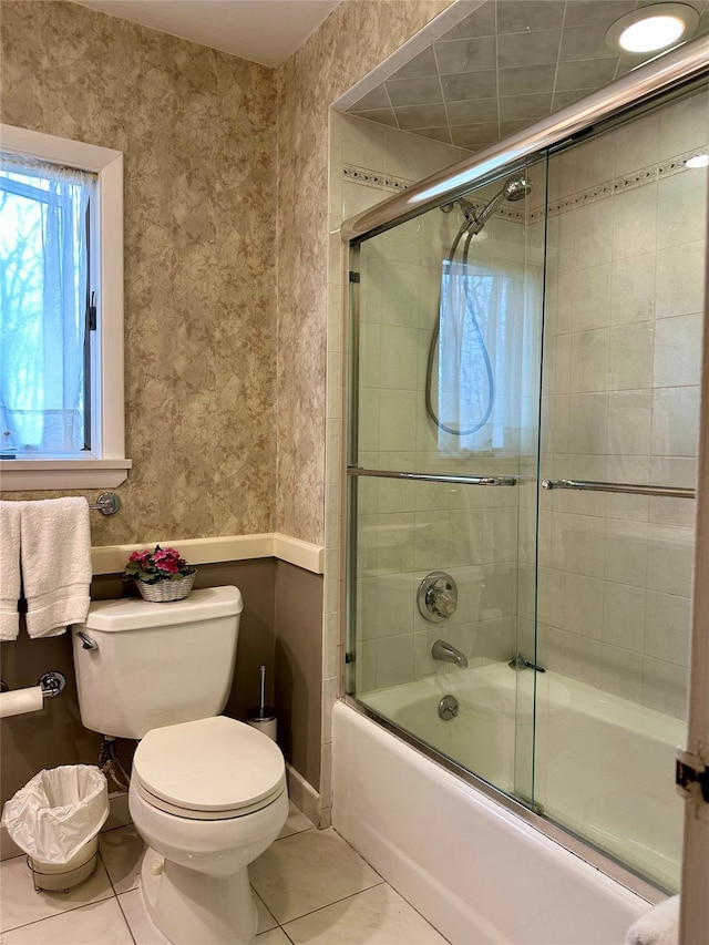 bathroom featuring tile patterned flooring, enclosed tub / shower combo, and toilet