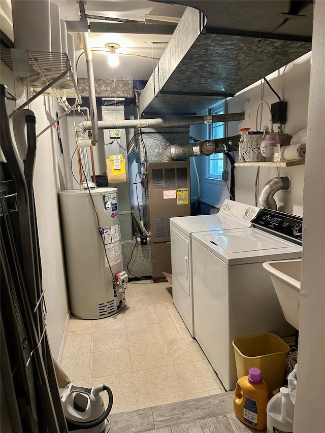 washroom with laundry area, a sink, washer and clothes dryer, and water heater