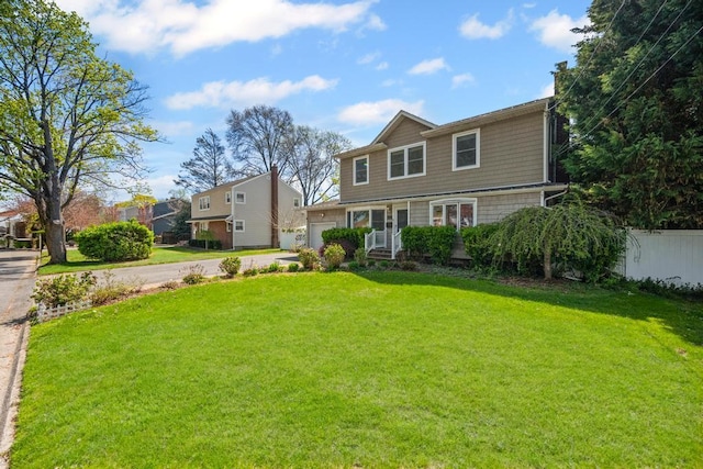 view of front of house with fence, a front yard, driveway, and an attached garage