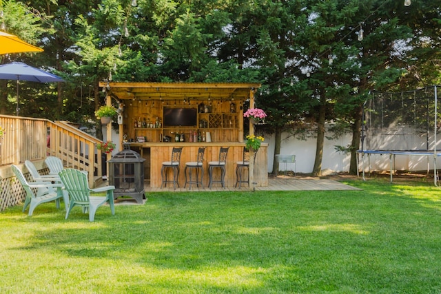 view of outbuilding featuring outdoor dry bar, fence private yard, and a trampoline