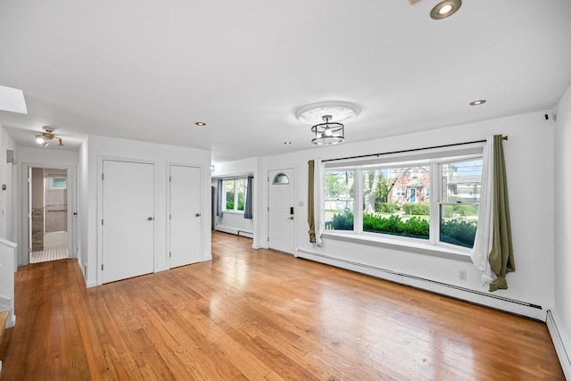 unfurnished living room with light wood finished floors, recessed lighting, an inviting chandelier, and baseboard heating
