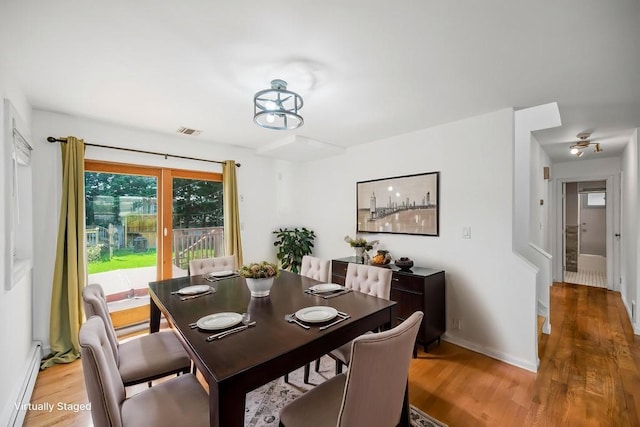 dining room featuring baseboards, visible vents, light wood-style flooring, and a baseboard radiator