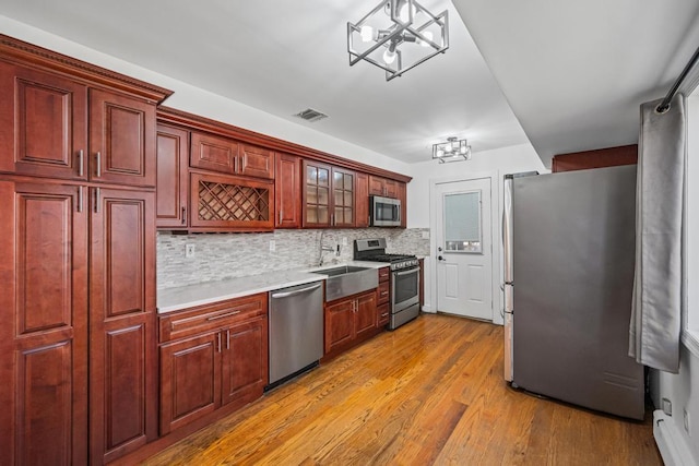 kitchen featuring an inviting chandelier, appliances with stainless steel finishes, visible vents, dark brown cabinets, and a baseboard radiator