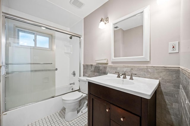 full bath featuring tile patterned floors, wainscoting, tile walls, vanity, and visible vents