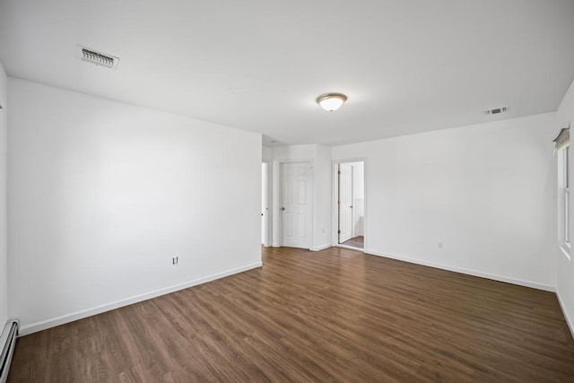 unfurnished room with dark wood finished floors, visible vents, baseboard heating, and baseboards
