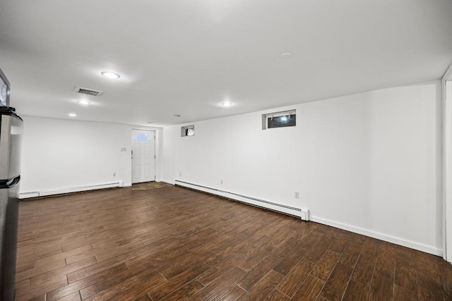 finished below grade area featuring recessed lighting, visible vents, baseboard heating, and wood finished floors