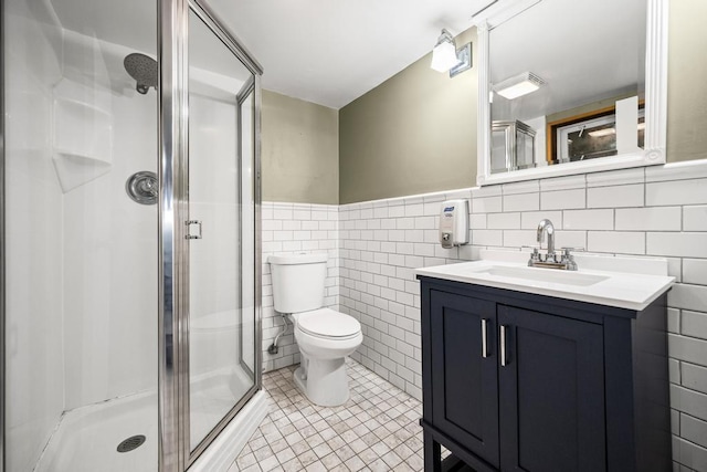 full bath with vanity, tile walls, a shower stall, and tile patterned floors