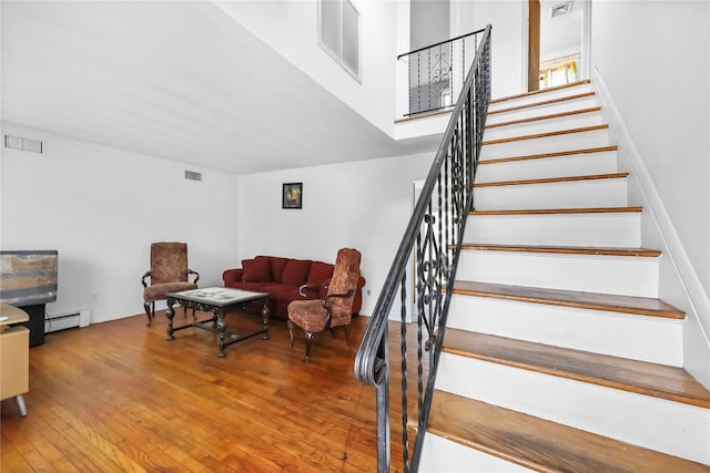 staircase with visible vents, a baseboard radiator, and wood finished floors