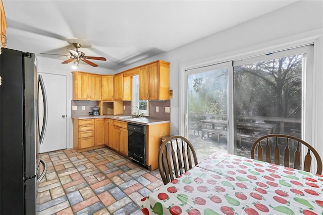 kitchen with freestanding refrigerator, ceiling fan, black dishwasher, light countertops, and a sink