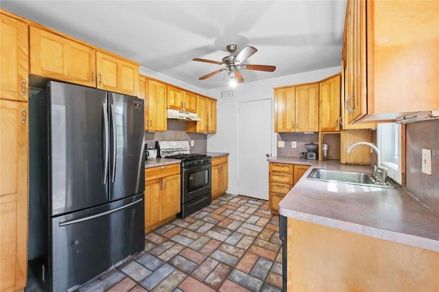 kitchen featuring freestanding refrigerator, ceiling fan, under cabinet range hood, a sink, and gas stove