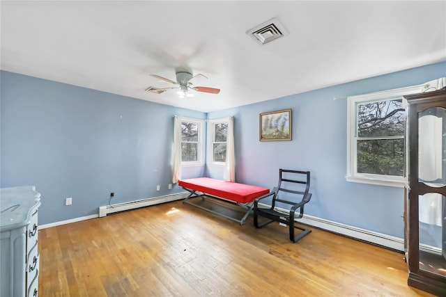 interior space with multiple windows, baseboard heating, light wood-type flooring, and visible vents