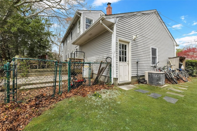 view of property exterior with fence, cooling unit, a chimney, a gate, and a lawn