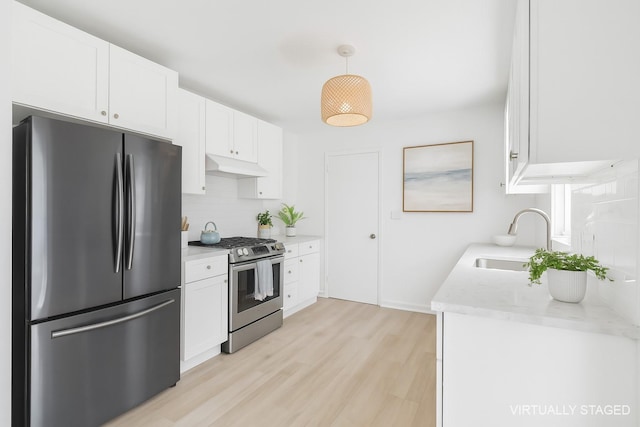 60 School St, Hampton Bays, NY 11946 - kitchen featuring stainless steel appliances, backsplash, light wood-style flooring, white cabinets, and under cabinet range hood