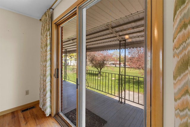 doorway to outside with baseboards, hardwood / wood-style floors, and visible vents