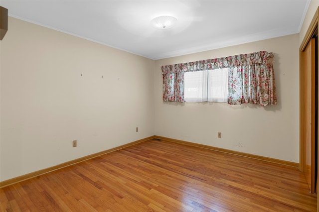 spare room featuring baseboards, ornamental molding, and light wood-type flooring