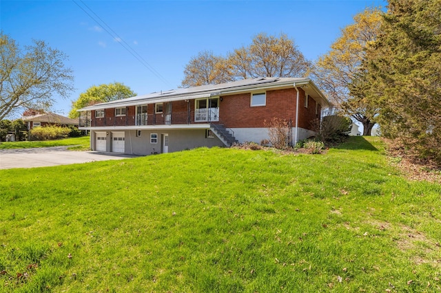 back of property featuring a garage, stairway, brick siding, roof mounted solar panels, and concrete driveway