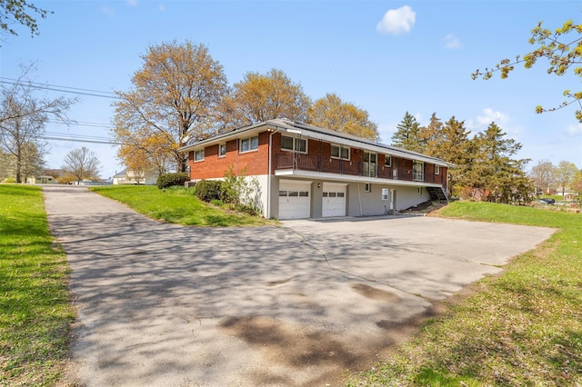 view of front of property featuring brick siding, driveway, a front lawn, and a garage