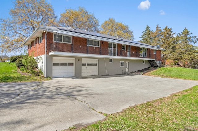 view of front facade with driveway, solar panels, a front yard, brick siding, and an attached garage