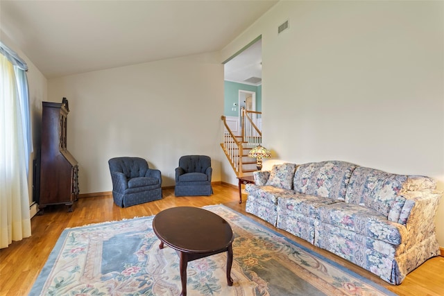 living room featuring visible vents, stairs, and wood finished floors