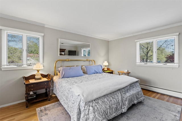 bedroom featuring crown molding, multiple windows, a baseboard heating unit, and wood finished floors