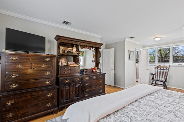 bedroom with light wood-style floors, baseboards, ornamental molding, and visible vents