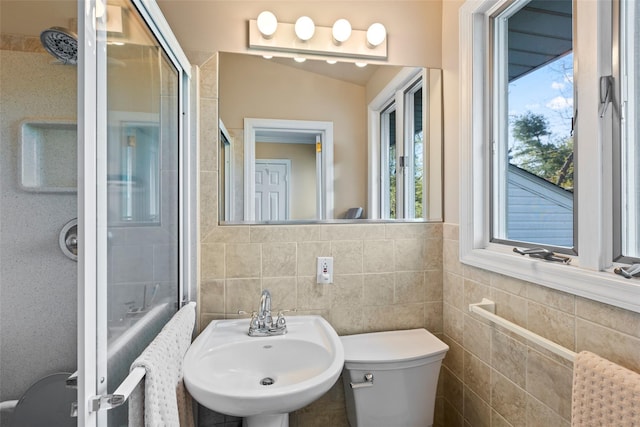 full bath with a sink, tile walls, a stall shower, and a wealth of natural light