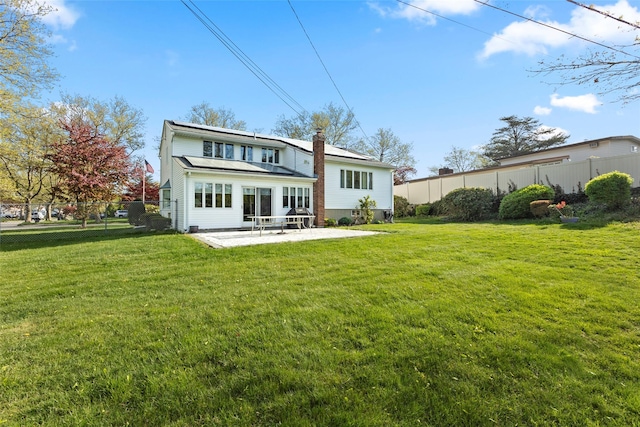 rear view of house featuring a lawn, fence, a patio, and a chimney