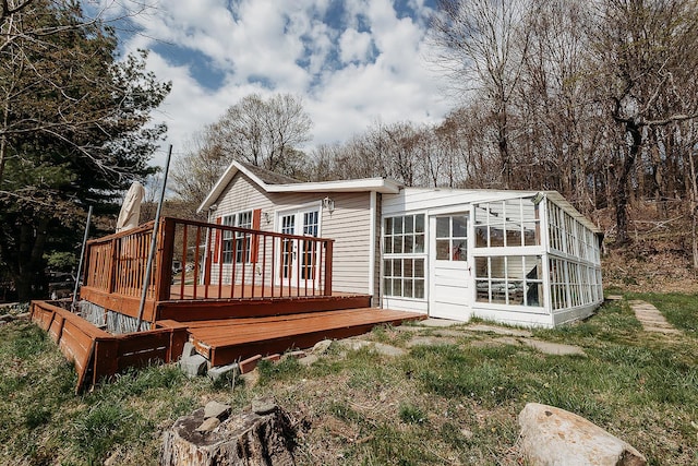 rear view of house with french doors, a wooden deck, and a sunroom