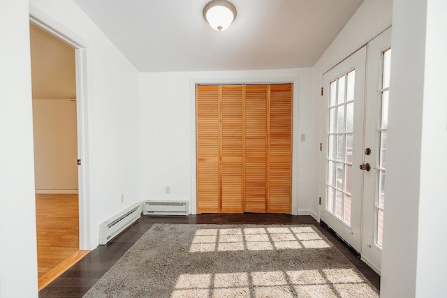 unfurnished bedroom with french doors, wood finished floors, multiple windows, and a baseboard radiator