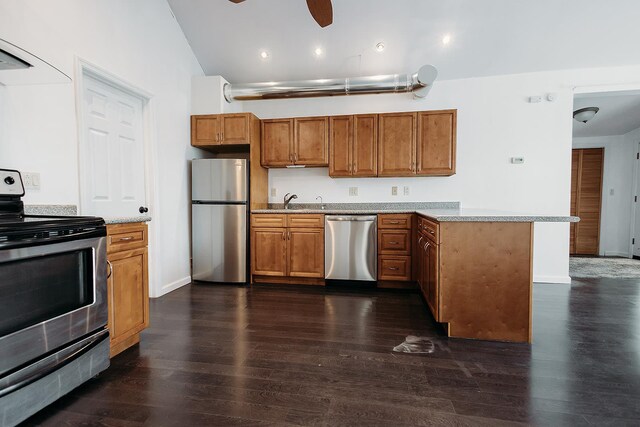 kitchen featuring dark wood-style flooring, brown cabinetry, a peninsula, light countertops, and appliances with stainless steel finishes