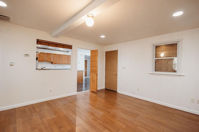 spare room featuring beam ceiling, light wood-type flooring, recessed lighting, and baseboards