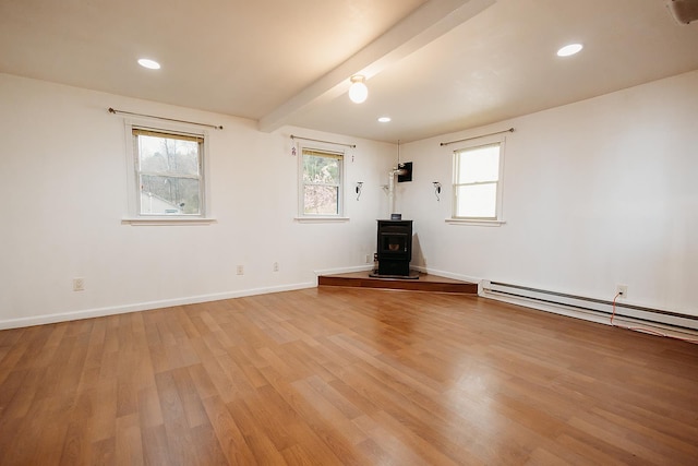 unfurnished living room featuring beamed ceiling, a wood stove, light wood finished floors, and baseboards