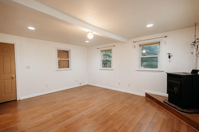 unfurnished living room with light wood-type flooring, recessed lighting, a wood stove, and baseboards
